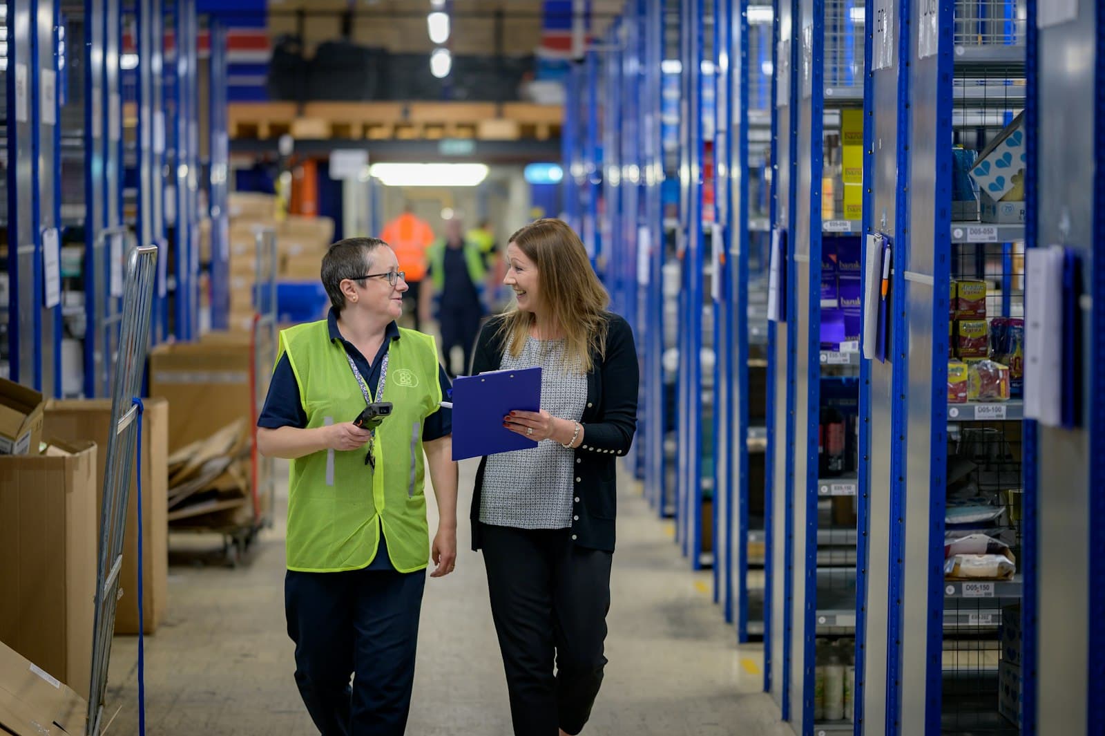 Two people walking a warehouse aisle